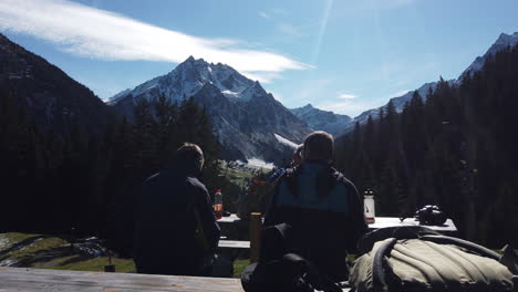 3-Hombres-Austriacos-Sentados-Junto-A-La-Mesa-Lateral-Con-Vista-A-La-Montaña-En-El-Fondo