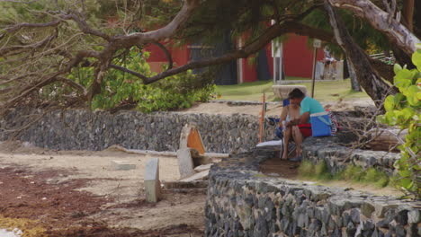 Couple-sit-on-rock-wall-overlooking-water-with-picnic-in-San-Juan,-Puerto-Rico