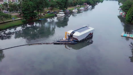 Toma-Aérea-De-Paralaje-Del-Robot-De-Limpieza-Del-Río-Interceptor-En-El-Río-De-Drenaje-Cengkareng