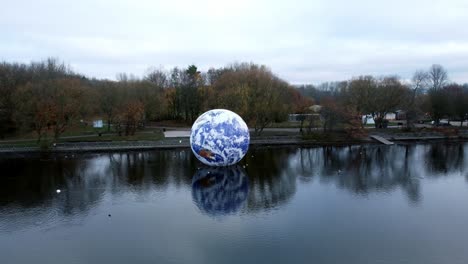 Luke-Jarram-Flotante-Tierra-Arte-Exposición-Vista-Aérea-Pennington-Destello-Lago-Naturaleza-Parque-Creciente-Tirar-Hacia-Atrás