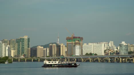 Hangang-Flussfähre,-Kreuzfahrtschiff-Mit-Touristen,-Die-Entlang-Des-Han-Flusses-Mit-Malerischem-Seouler-Stadtpanorama-Segeln---Wahrzeichen-Seouls,-Namsan-Turm,-Mapodaegyo-Brücke,-Gangbyeon-Schnellstraße,-Tagsüber-Im-Sommer