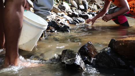 Woman-and-her-small-girl-clearing-stones-in-river-to-make-it-clean-for-doing-laundry