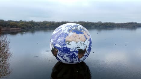 Luke-Jarram-floating-earth-exhibition-aerial-view-at-Pennington-flash-park-lake-rising-tilt-down