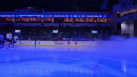 A-male-hockey-player-holding-his-hockey-stick-comes-out-from-the-fog-to-line-up-with-his-teammates-on-the-rink