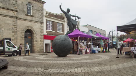 Escultura-De-Bronce-Del-Baterista-En-Lemon-Quay-Con-Farmer&#39;s-Market-En-Segundo-Plano-En-Truro,-Cornualles,-Reino-Unido