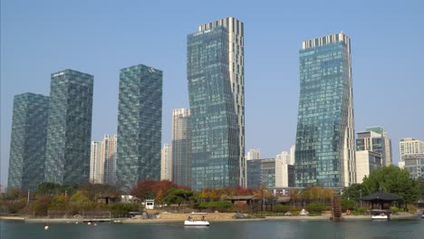 Los-Edificios-Futuristas-Del-Complejo-De-Apartamentos-Del-Parque-Central-De-Incheon-Songdo-Se-Ven-Contra-El-Cielo-Despejado-Desde-El-Paseo-Marítimo-Del-Lago-En-Otoño---Paisaje-Estático