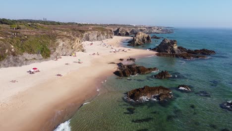 Playa-Praia-Da-Samoqueira-Cerca-De-Porto-Covo,-Alentejo,-Oeste-De-Portugal---Vista-Aérea-De-Drones-De-Turistas-Relajándose-En-La-Playa-De-Arena-Dorada