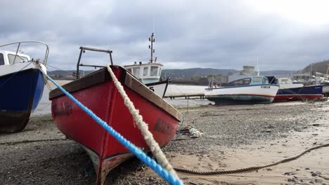 Leere-Boote-Vertäut-Am-Kiesstrand-Am-Wasser-Bei-Ebbe-Im-Fischereihafen-Von-Nordwales