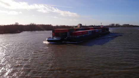 Vista-Aérea-De-La-Proa-Delantera-Del-Barco-Del-Milenio-Y-Barcazas-Que-Transportan-Contenedores-De-Carga-A-Lo-Largo-De-Oude-Maas