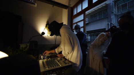 Time-lapse-of-Asian-guy-wearing-face-mask-while-playing-tunes-while-adjusting-DJ-mixer-console-during-live-DJ-music-performance