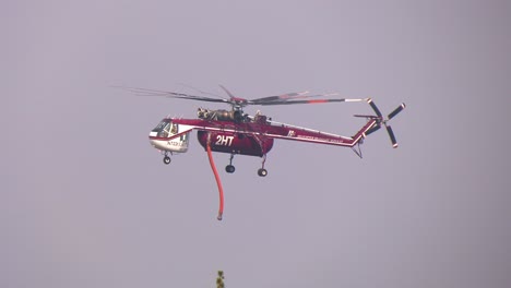 Firefighter-helicopter-flying-over-forest,-during-wildfires---slow-motion-view