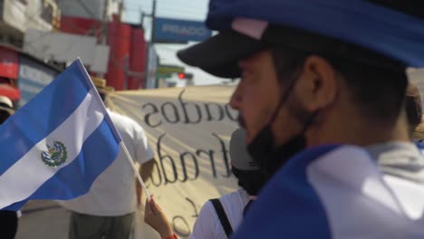 Salvadoran-walks-with-the-national-flag-during-a-peaceful-protest-in-the-city-streets-against-current-president-Nayib-Bukele---slow-motion