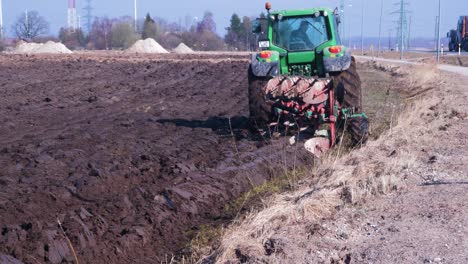 Der-Grüne-Ackerschlepper-Pflügt-Trockenes-Land-Auf-Dem-Feld,-Sonniger-Frühlingstag,-Mittlere-Handaufnahme