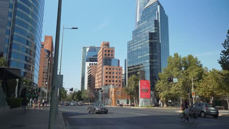 Tilt-down-of-commuter-vehicles-in-modern-avenue-with-luxurious-buildings-at-daytime,-Santiago,-Chile