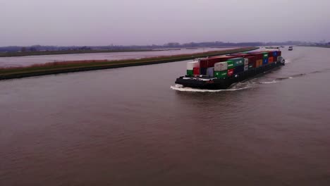 Vista-Aérea-Del-Barco-Fps-Rijn-Que-Transporta-Contenedores-En-El-Río-Noord-En-Una-Tarde-Nublada