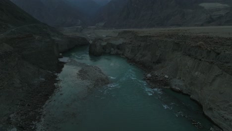 Vuelo-Aéreo-De-Regreso-Al-Agua-De-Río-De-Color-Turquesa-En-El-Valle-De-Hunza-En-Un-Día-Nublado-De-Mal-Humor-Oscuro