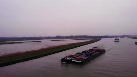 Vista-Aérea-Del-Buque-De-Carga-Maas-Emparejado-Con-Otro-Que-Transportaba-Contenedores-De-Carga-En-El-Río-Noord-En-Una-Tarde-Nublada