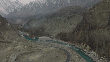 Inclinación-Aérea-Hacia-Abajo-Desde-Las-Montañas-Cubiertas-De-Nieve-Hasta-El-Río-Hunza-Valley