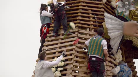 Camera-tilts-up-to-show-male-Falleros-adding-flowers-to-the-Lady-of-the-Forsaken-statue-during-the-Fallas-Ofrenda-festival-in-Valencia