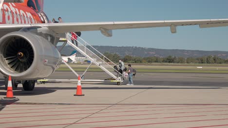 Passagiere,-Die-An-Einem-Sonnigen-Tag-Ein-Verkehrsflugzeug-Besteigen-Und-Vom-Rollfeld-Draußen-Die-Rampe-Zum-Flugzeug-Hinaufgehen