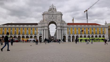 Slow-motion-view-of-Commerce-Square-in-Lisbon,-Portugal-filled-with-tourists-visiting-the-capitol-city,-historic-landmarks-and-buildings