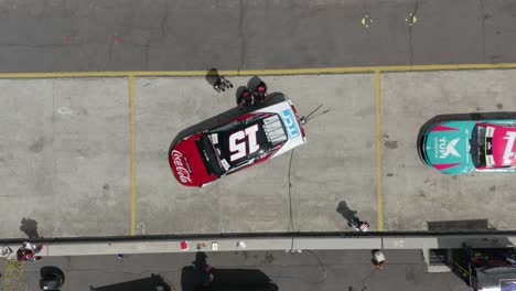 Top-down-view-of-Racing-team-working-at-pit-stop,-formula-1