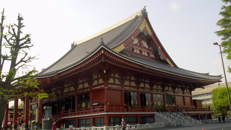 Asakusa,-Tokio,-Japón,-Alrededor-De-Abril-De-2020:-Gente-Caminando-En-Un-Auténtico-Templo-Japonés-Con-Una-Hermosa-Decoración-Artesanal-En-El-Techo-Y-La-Pared-En-El-Soleado-Día-De-Primavera