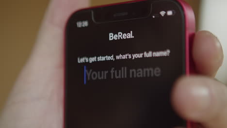 Bereal-Logo-App-Symbol-Auf-Dem-Bildschirm-Des-Mobiltelefons,-Fingertippen-Auf-Dem-Display,-Um-Die-Anwendung-Zu-Starten