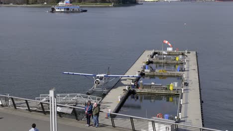 Pareja-Adulta-Posa-Para-Una-Foto-En-El-Puerto-De-Vancouver-Con-Hidroavión-Atracado-En-Segundo-Plano.