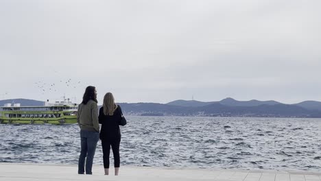 Una-Pareja-Enamorada-Viendo-Pasar-Los-Barcos-En-Un-Hermoso-Paseo-Marítimo-En-Zadar,-Croacia