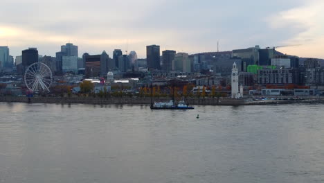 Barco-Navegando-En-El-Río-Saint-laurent,-Puerto-Viejo,-Montreal,-Quebec,-Canadá,-Rueda-De-La-Fortuna,-Torre,-Edificios,-Centro-De-Montreal,-Paisaje-Urbano,-Vista-Aérea-Del-Horizonte-Por-Drone