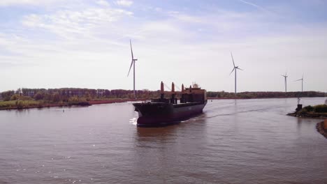 Luftaufnahme-Des-Frachtschiffs-Aal-Paris,-Das-Sich-Entlang-Der-Oude-Maas-Nähert,-Mit-Noch-Windkraftanlagen-Im-Hintergrund-In-Barendrecht