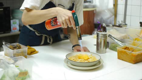 Chef-using-gas-torch-to-scorch-surface-of-egg-and-noodle-dish-in-kitchen-filmed