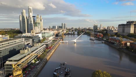 Backward-aerial-of-Puente-de-la-Mujer-and-Puerto-Madero,-Buenos-Aires