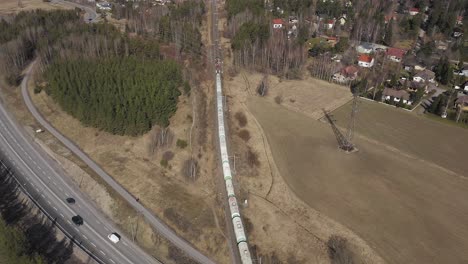 Vista-Aérea-De-Un-Largo-Tren-De-Carga-Que-Viaja-Por-Un-Paso-Elevado