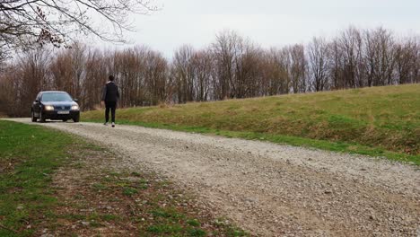 Joven-Corriendo-Hacia-Su-Coche-En-Una-Carretera-Rural