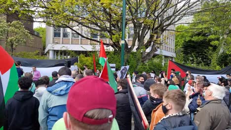 Disparo-De-Un-Camión,-Pasando-Junto-A-Una-Protesta-Palestina-En-Dublín-Con-Gente-Sosteniendo-Banderas