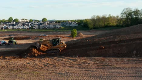 CAT-Caterpillar-bulldozer-pushes-earth-and-dirt,-preparing-excavation-site-for-road-and-housing-construction