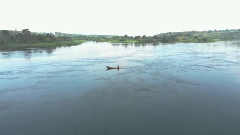 Antena-Orbitando-Alrededor-De-Un-Hombre-Africano-En-Un-Barco-De-Pesca-Tradicional-Remando-Aguas-Arriba-En-El-Río-Nilo