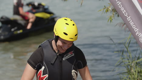 Junger-Mann-Mit-Helm-Und-Neoprenanzug-Lächelt-In-Die-Kamera,-Nachdem-Er-Auf-Dem-Meer-Flyboard-Gefahren-Ist