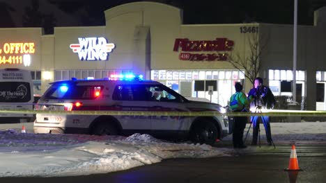 Police-officers-standing-next-to-a-police-vehicle-in-a-crime-scene-marked-with-keep-out-tape