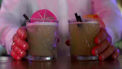 Bartender-putting-colorful-umbrellas-in-tropical-cocktail-on-bar-counter,-finishing-touch