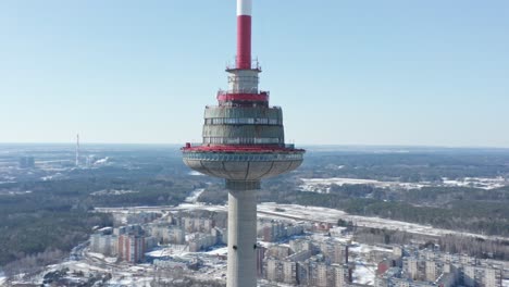 Primer-Plano-Aéreo-Drone-De-La-Torre-De-Televisión-De-Vilnius-Con-Ciudad-Y-Bosque-En-Invierno