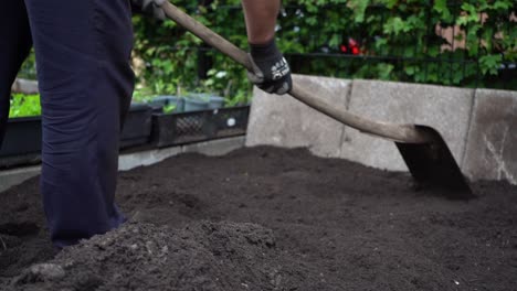 Nahaufnahme-Einer-Männlichen-Figur,-Die-Den-Boden-Eines-Gartenblumenbeets-Mit-Einer-Schaufel-Ebnet