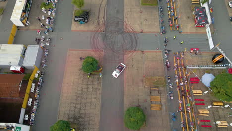 Vista-Aérea-De-Un-Auto-Deportivo-Blanco-A-La-Deriva-En-La-Arena-Durante-El-Espectáculo-De-Acrobacias