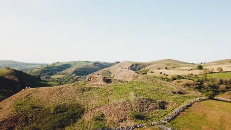 Dron-Aéreo-En-El-Sentido-De-Las-Agujas-Del-Reloj-Disparado-Desde-Detrás-De-La-Cueva-De-Thor,-Ashbourne,-Peak-District,-Inglaterra-Hacia-Un-Lado