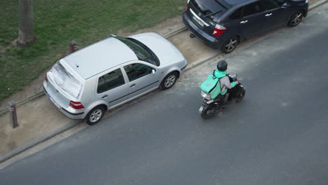 Draufsicht-Auf-Den-Deliveroo-Fahrer-Auf-Einem-Roller,-Der-Unterwegs-Ist,-Um-Die-Nächste-Bestellung-Beim-Kunden-Auszuliefern