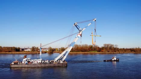 Luftaufnahme-Eines-Schwimmenden-Sheerlegs,-Das-Tagsüber-Von-Einem-Schlepper-über-Den-Bach-In-Barendrecht,-Niederlande,-Gezogen-Wird