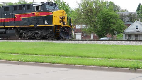 Die-Lokomotive-Der-Iowa-Interstate-Railroad-Schiebt-Den-Zug-Langsam-Die-Gleise-Hinunter,-Vorbei-An-Verkehr-Und-Häusern