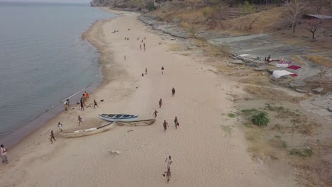 Sonrientes-Niños-Tumbuka-Africanos-Persiguen-Drones-A-Lo-Largo-De-La-Orilla-Del-Lago-Malawi